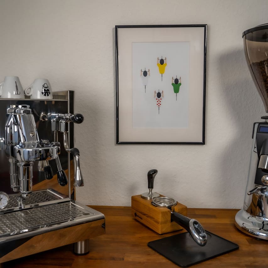 Das Poster "Helden der Landstraße" hängt im Bilderrahmen an der Wand zwischen einer Kaffeemaschine und einer Kaffeemühle.