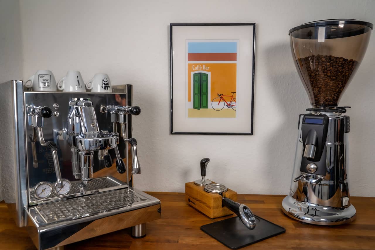 Das Poster "Caffè Bar" hängt im Bilderrahmen an der Wand zwischen einer Kaffeemaschine und einer Kaffeemühle.