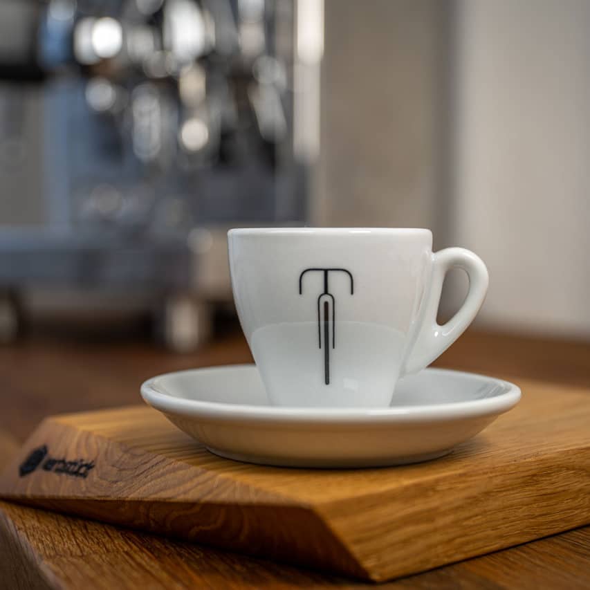 Eine weiße Espresso-Tasse mit einem stilisierten Rennrad.