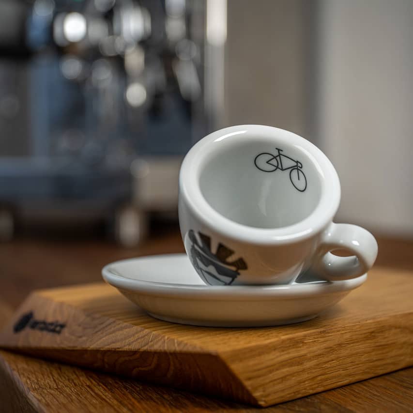 Eine Espresso-Tasse liegt auf der Seite, auf dem inneren Tassenrand ist ein Rennrad abgedruckt.